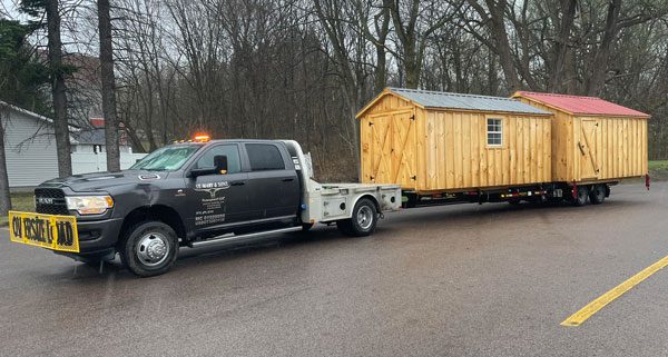 St Mary & Sons Truck with Oversized Load Sign towing two Amish Sheds